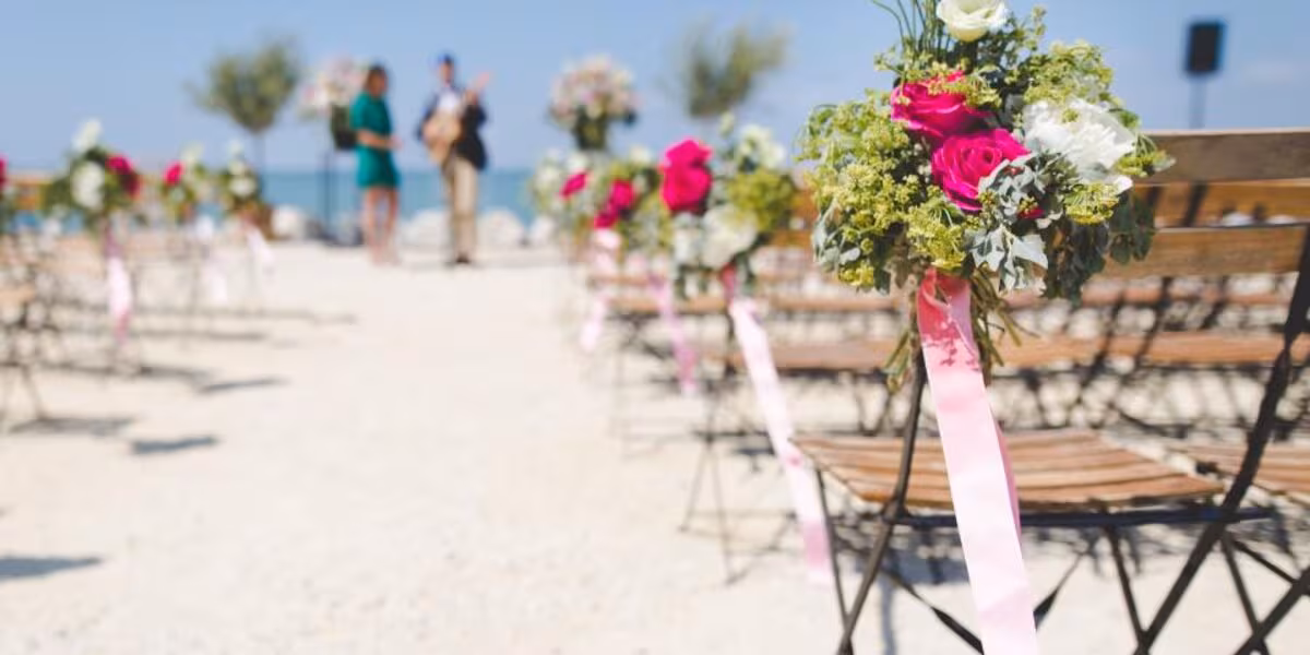 Pasillo de ceremonia en la playa con sillas y arreglos florales