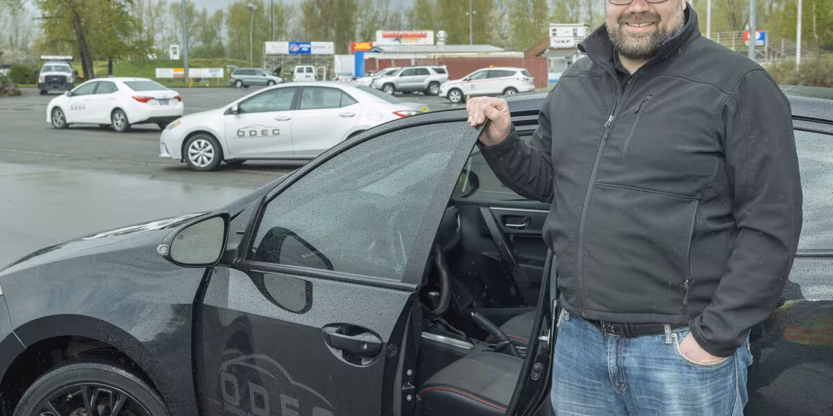Instructor de manejo junto a un automóvil de práctica