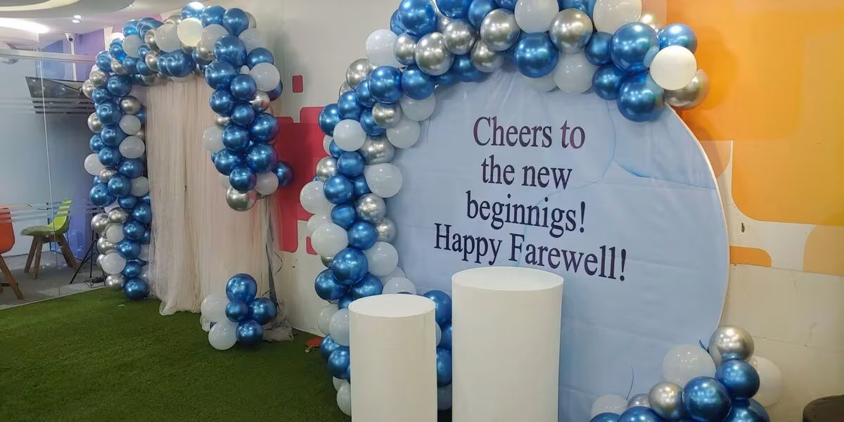 Arco de globos plateados, azules y blancos alrededor de un letrero de festejo