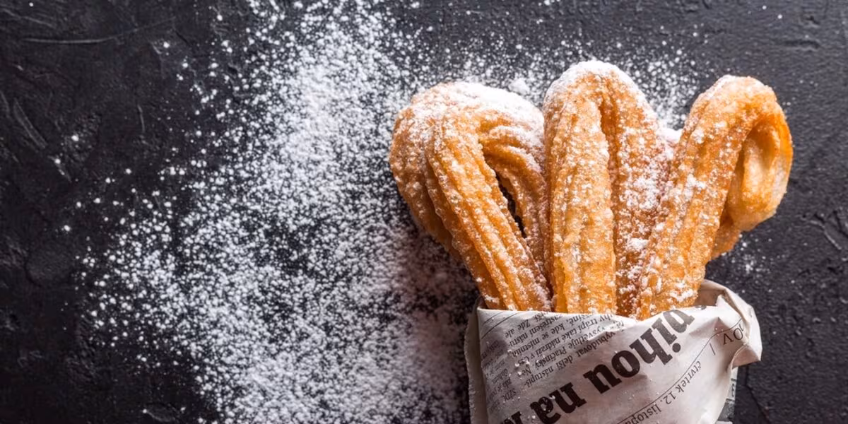 Churros espolvoreados con azúcar servidos en cucurucho de papel