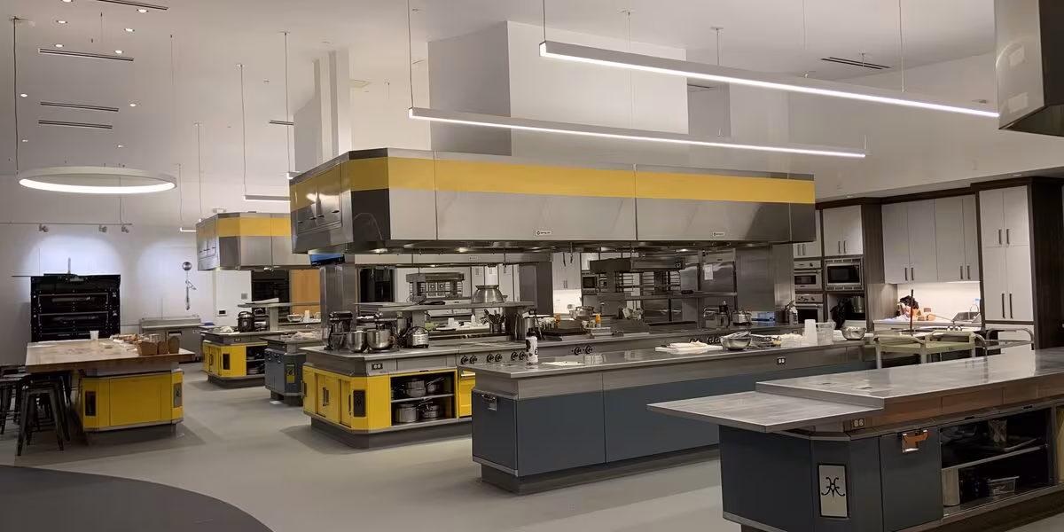Cocina industrial de acero inoxidable con estaciones de trabajo y campanas de extracción