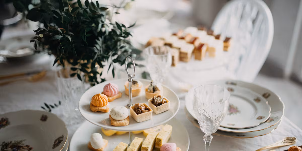 Mesa de postres con bocadillos y arreglos florales en una recepción