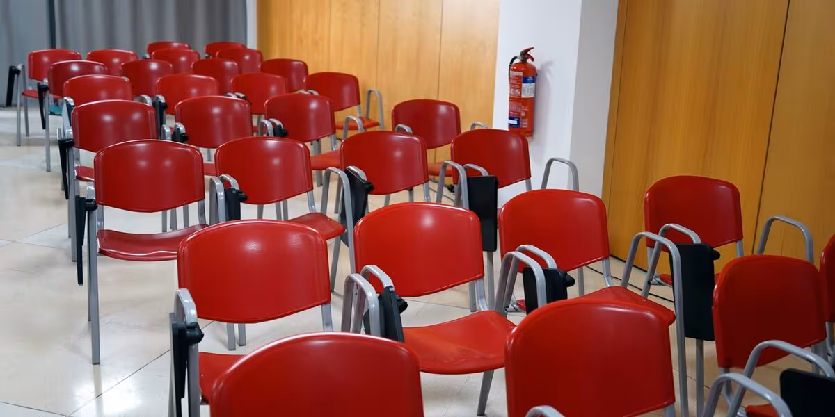 Sala de capacitación con sillas rojas y un extintor montado en la pared