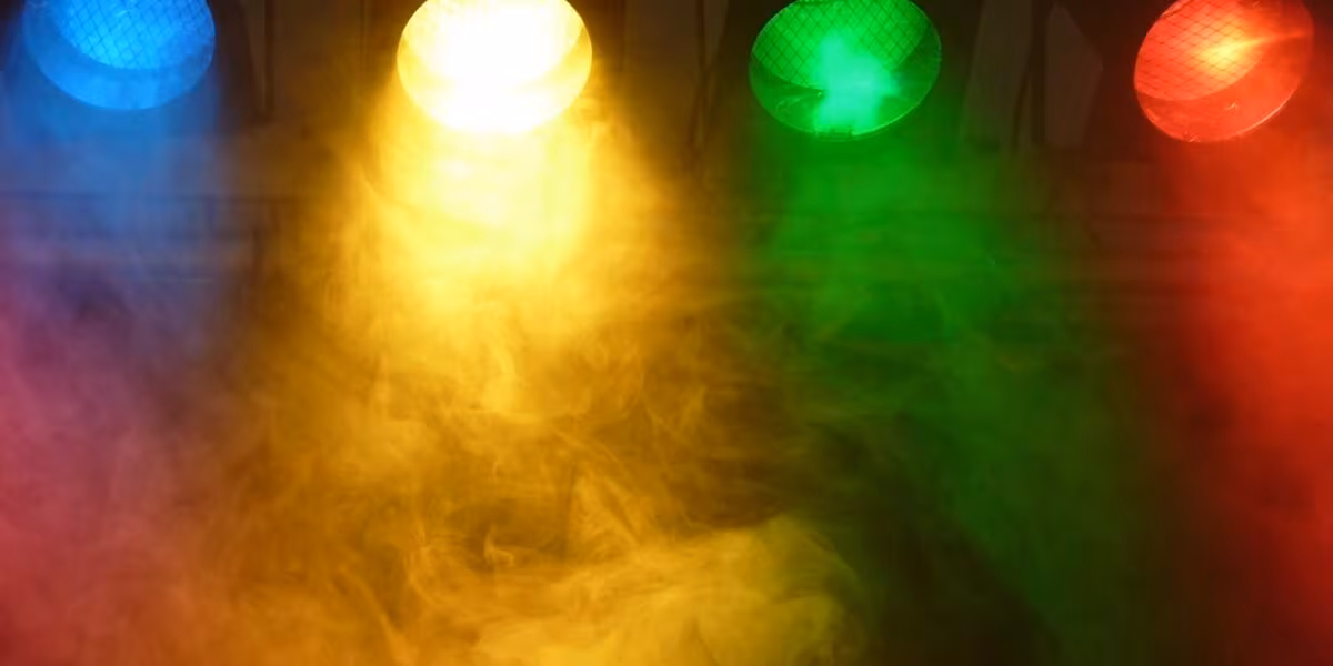 Reflectores de colores iluminando un escenario con humo