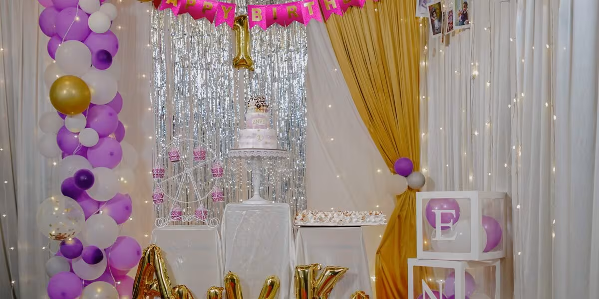 Escenario de cumpleaños decorado con globos morados y pastel