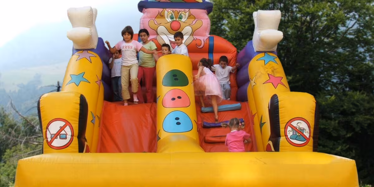 Niños en un tobogán inflable con malla de protección